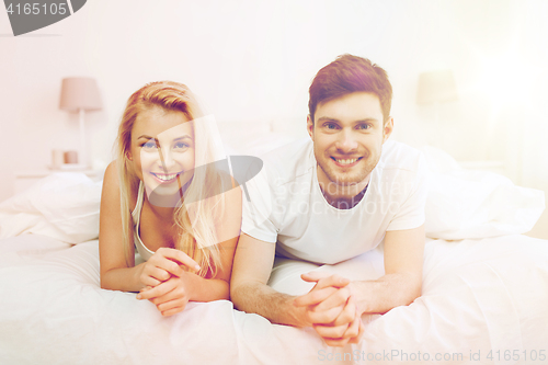 Image of happy couple lying in bed at home