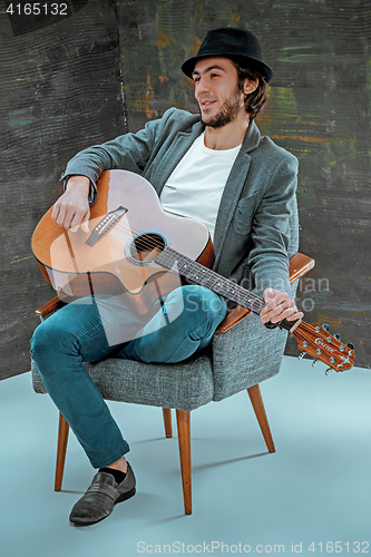 Image of Cool guy with hat playing guitar on gray background