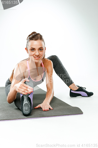 Image of Beautiful slim brunette doing some stretching exercises in a gym