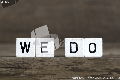Image of We do, written in cubes on wooden background