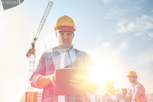 Image of builder in hardhat with tablet pc at construction