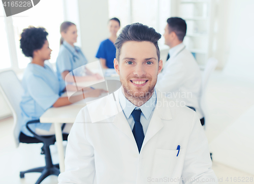 Image of happy doctor over group of medics at hospital