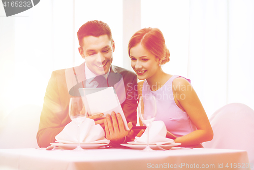 Image of couple with menus on tablet pc at restaurant