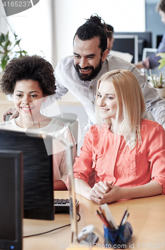 Image of happy creative team with computer in office