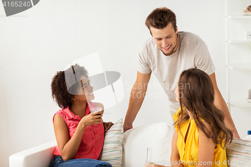 Image of group of happy friends with drinks talking at home