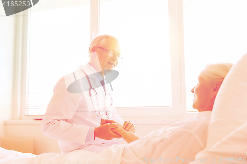 Image of doctor checking senior woman pulse at hospital