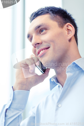 Image of smiling businessman with smartphone in office