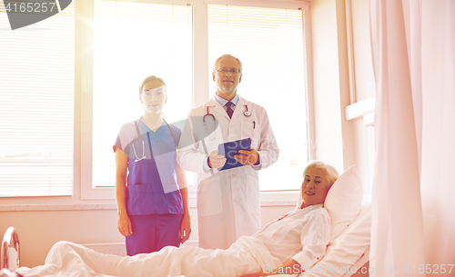 Image of doctor and nurse visiting senior woman at hospital