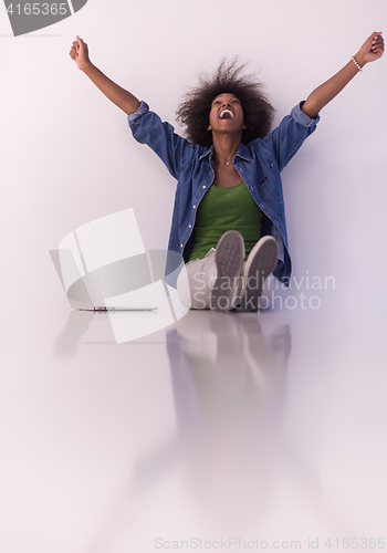 Image of african american woman sitting on floor with laptop