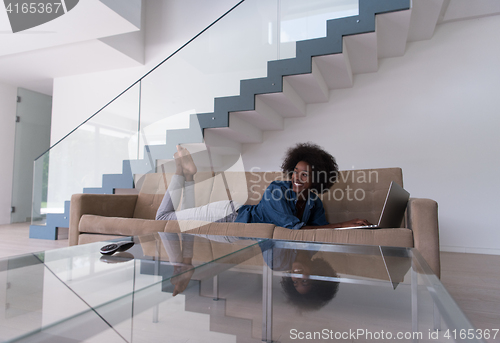 Image of African American woman using laptop on sofa