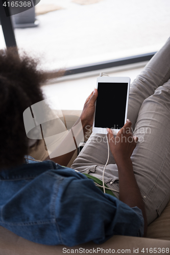 Image of African american woman at home in chair with tablet and head pho