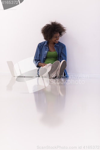 Image of african american woman sitting on floor with laptop