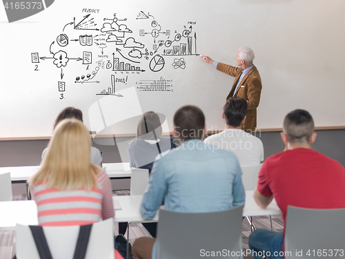 Image of senior professor with students on course