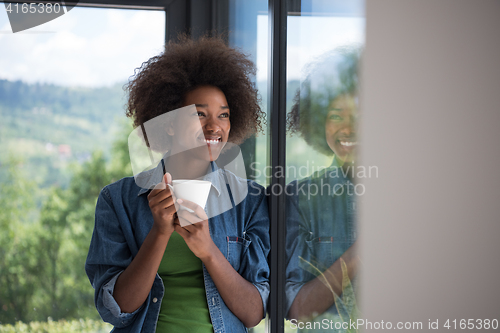 Image of African American woman drinking coffee looking out the window