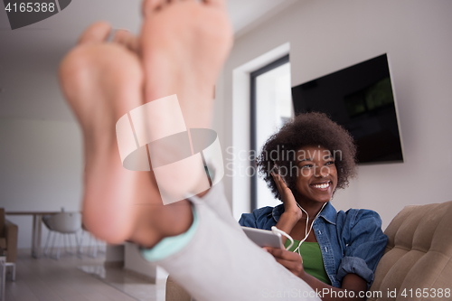 Image of African american woman at home in chair with tablet and head pho