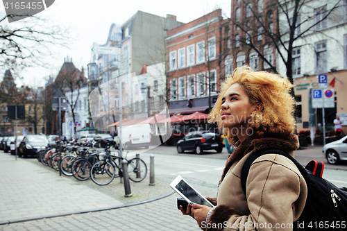 Image of young pretty african american girl with curly hair making photo on a tablet, lifestyle people concept, tourist in european german city