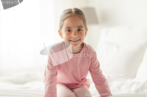 Image of happy little girl on bed at home bedroom