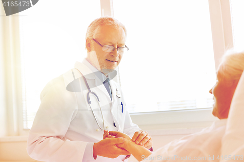 Image of doctor checking senior woman pulse at hospital