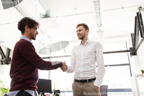 Image of happy businessmen making handshake at office