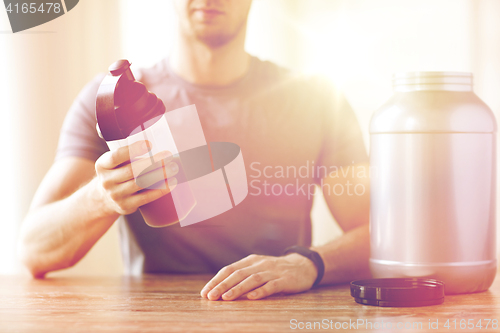 Image of close up of man with protein shake bottle and jar