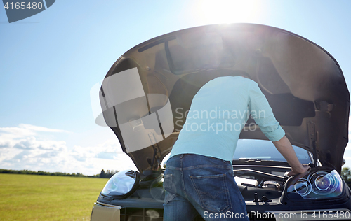 Image of man with open hood of broken car at countryside