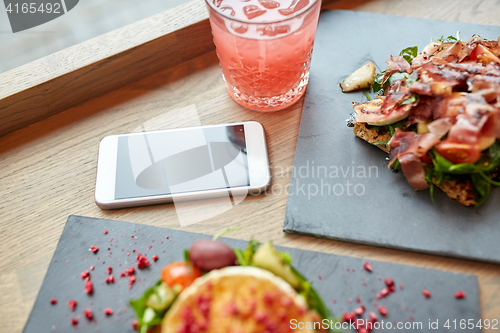 Image of goat cheese and ham salads with smartphone at cafe