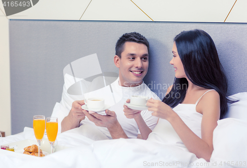 Image of smiling couple having breakfast in bed in hotel