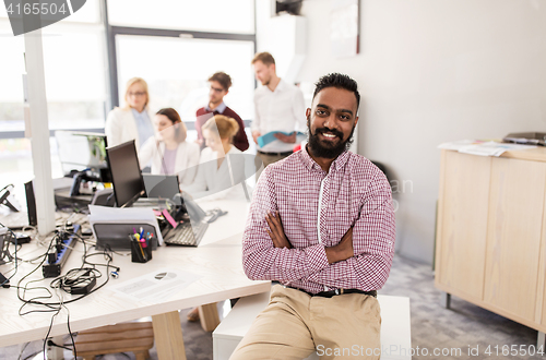 Image of happy indian man over creative team in office