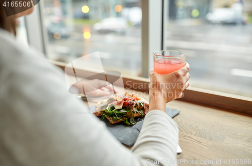 Image of woman with salad and glass of drink at restaurant