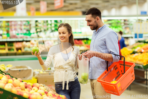 Image of happy couple buying apples at grocery store