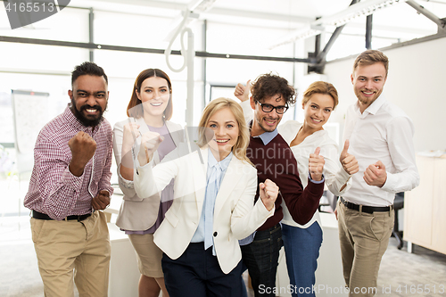 Image of happy business team celebrating victory at office