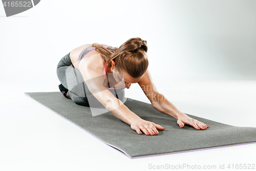 Image of Beautiful slim brunette doing some stretching exercises in a gym