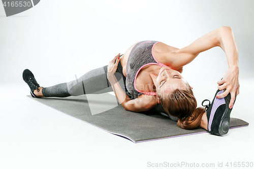 Image of Beautiful slim brunette doing some stretching exercises in a gym