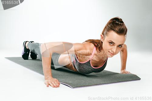 Image of Beautiful slim brunette doing some push ups a the gym