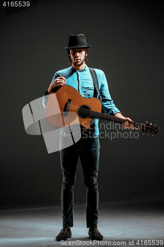 Image of Cool guy standing with guitar on dark background