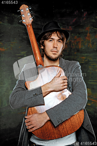 Image of Cool guy sitting with guitar on gray background