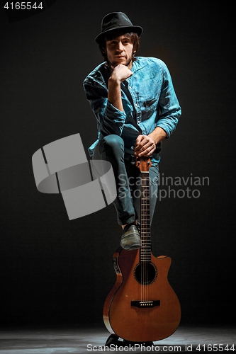 Image of Cool guy standing with guitar on dark background