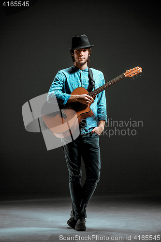 Image of Cool guy standing with guitar on dark background