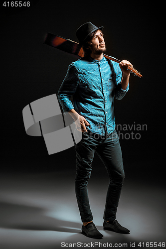 Image of Cool guy standing with guitar on dark background