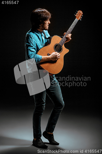 Image of Cool guy standing with guitar on dark background