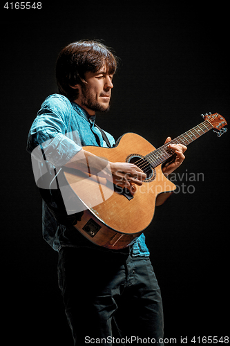 Image of Cool guy standing with guitar on dark background