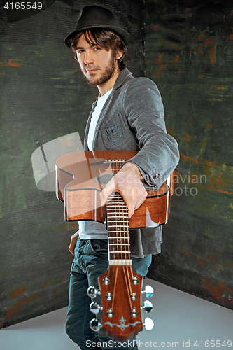 Image of Cool guy standing with guitar on gray background
