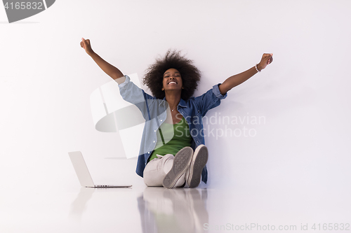 Image of african american woman sitting on floor with laptop