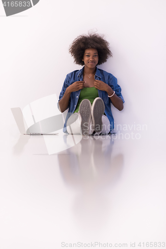 Image of african american woman sitting on floor with laptop