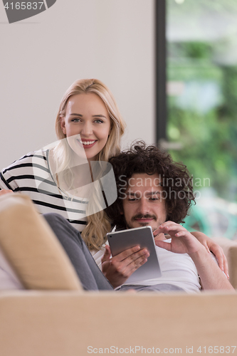 Image of couple relaxing at  home with tablet computers