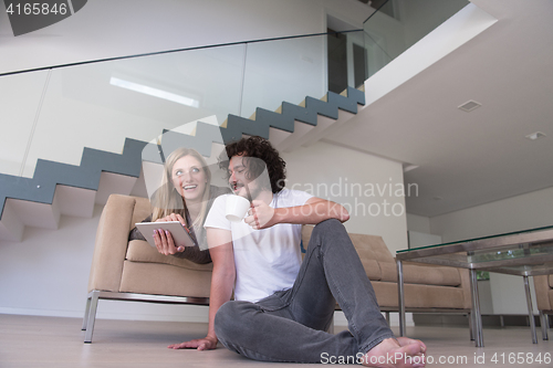 Image of couple relaxing at  home with tablet computers