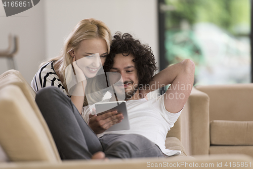 Image of couple relaxing at  home with tablet computers