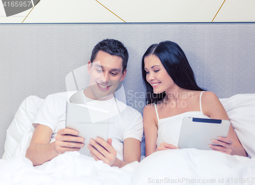 Image of smiling couple in bed with tablet pc computers