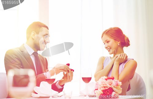 Image of man proposing to his girlfriend at restaurant