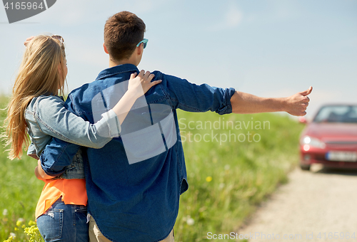 Image of couple hitchhiking and stopping car on countryside